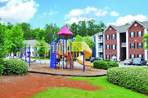 A playground with a yellow slide and a pink roof.