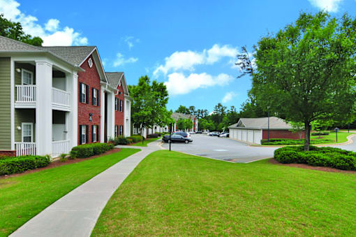 A street view of a residential area with houses on the left and a tree on the right.