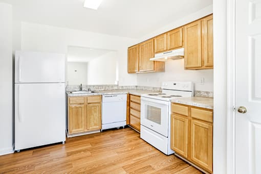 A kitchen with white appliances and wooden cabinets.