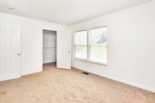 A room with a carpeted floor and a window with blinds.