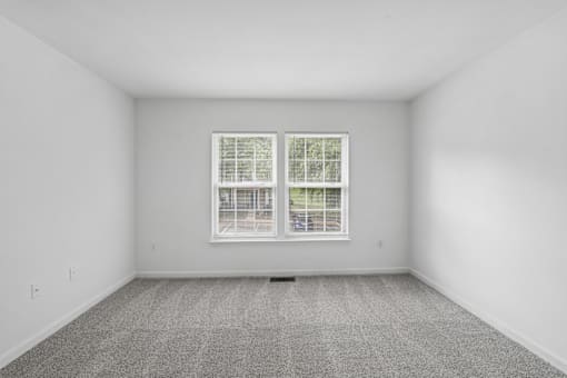 A room with a window and carpeted floor.