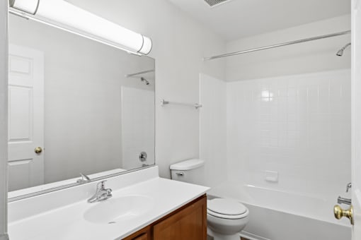 A white bathroom with a toilet, sink, and bathtub.