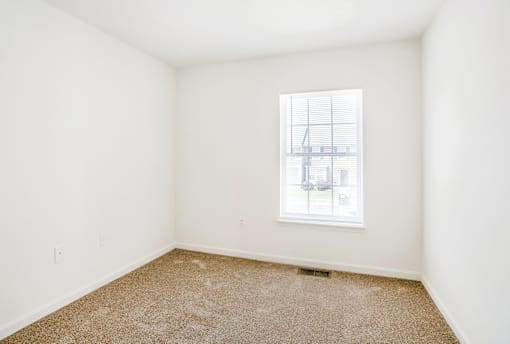 A room with a window and carpeted floor.