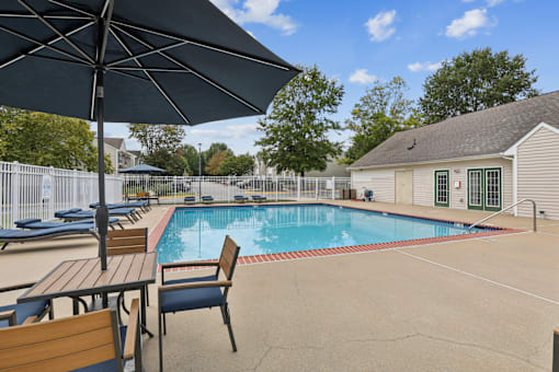 A pool with a table and chairs and an umbrella.