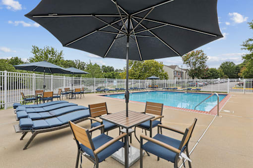 A black umbrella shades a table with four chairs.