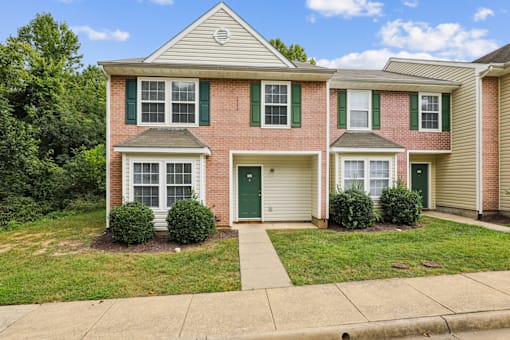 A red brick house with green shutters and a white door.