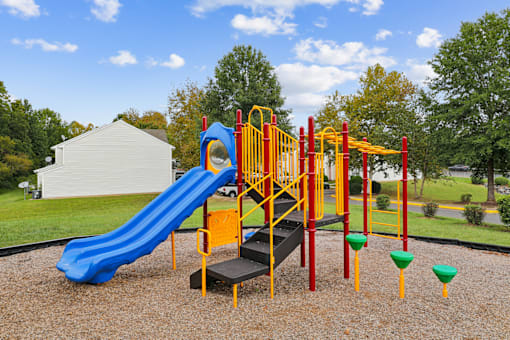A playground with a blue slide and yellow and red play structures.