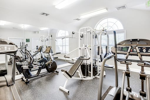 A gym with a variety of equipment including treadmills, weights, and exercise machines.