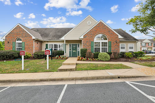 A brick house with a green door and a sign in front.