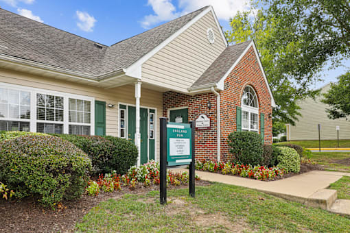 A sign in front of a brick building with a green door.