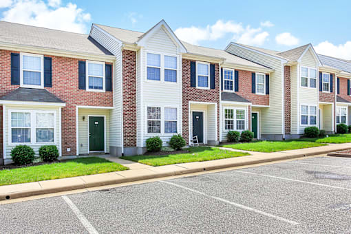 A row of townhouses with a parking lot in front.
