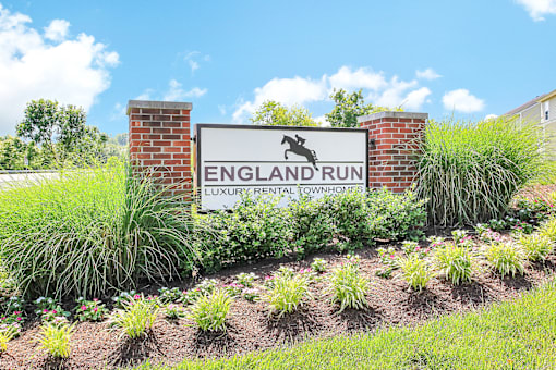A sign for England Run Luxury Rental Townhomes is displayed in a garden.