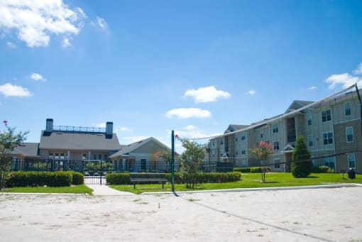 Sand Volleyball Court with Net and Sidewalk Through Shrubs with Leasing Office in the Background