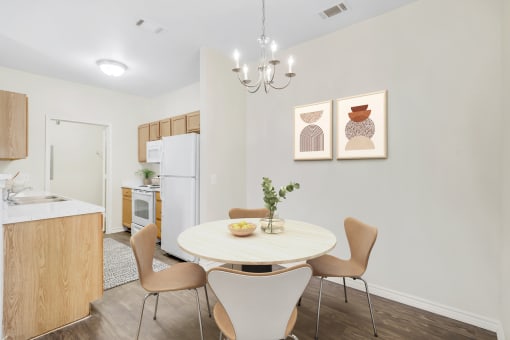 a dining area with a table and chairs and a kitchen in the background