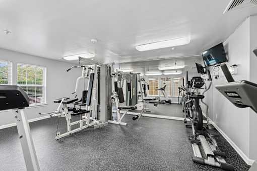 A spacious gym with a variety of equipment including treadmills, stationary bikes, and weight machines.