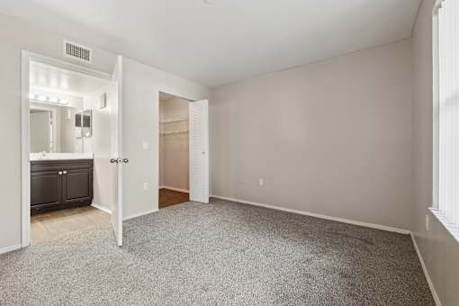 A spacious room with a carpeted floor and a doorway leading to another room.