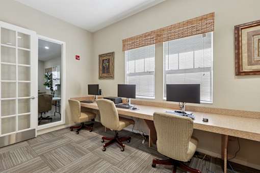 A room with a desk and chairs with a computer on it.
