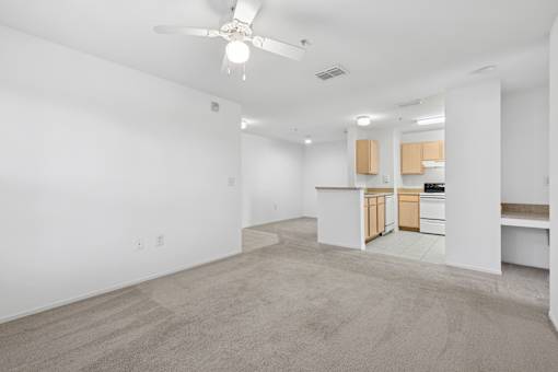 A spacious room with a ceiling fan and carpeted floor.