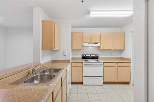 A kitchen with a sink, stove, and cabinets.