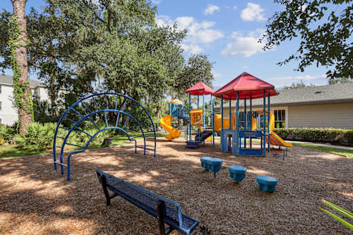 A playground with a red canopy and blue and yellow play equipment.
