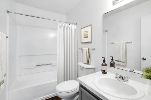 a bathroom with a white sink and toilet next to a white bathtub with a shower curtain