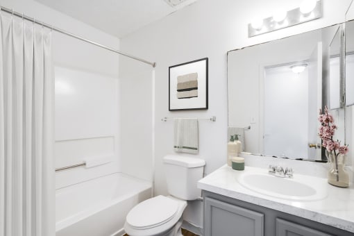 a bathroom with a white bathtub and a white toilet next to a sink with a mirror