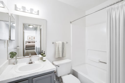 a bathroom with a white sink and toilet and a white bathtub with a shower curtain