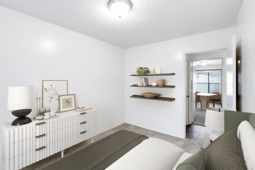 a bedroom with a bed and a dresser with a table in the background