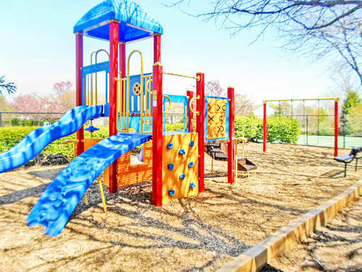 A playground with a blue slide and red climbing frame.