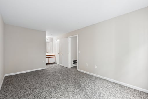 A room with a carpeted floor and a doorway leading to another room.