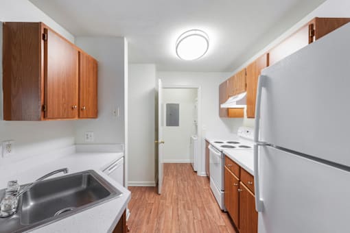 A kitchen with white appliances and wooden cabinets.