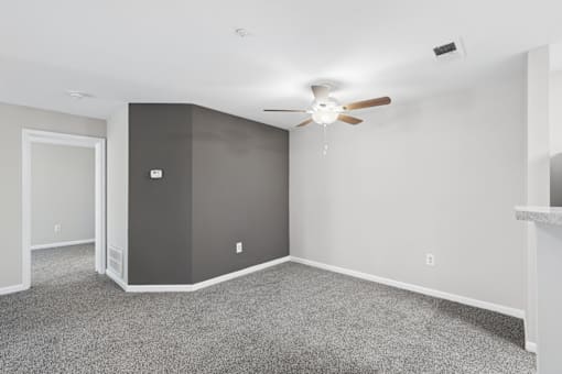 A room with a ceiling fan and carpeted floor.