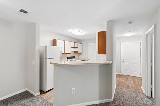 A kitchen with a refrigerator, island, and cabinets.