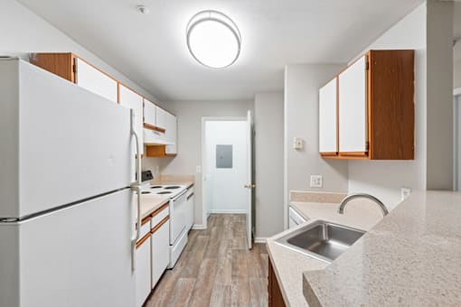 A kitchen with white appliances and wooden cabinets.