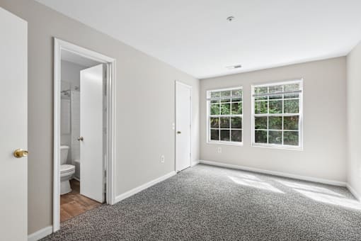 A white bathroom with a toilet, sink, and a door leading to another room.