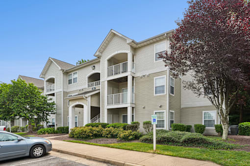 A large apartment building with a car parked in front.