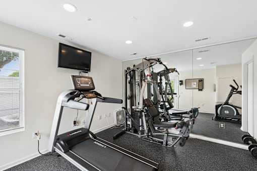 A home gym with a treadmill, weights, and exercise equipment.