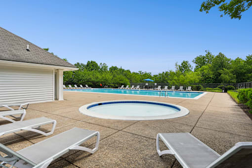 A pool surrounded by trees and chairs.