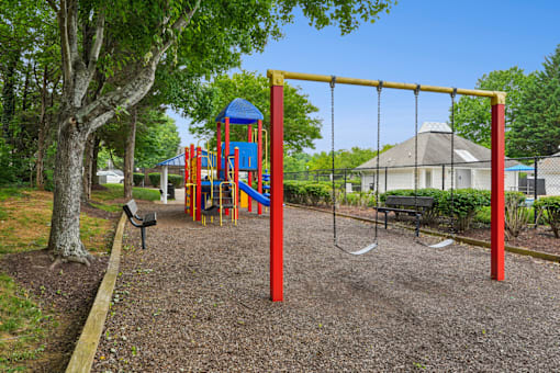 A playground with a red swing set and a blue slide.