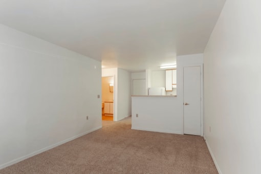 Open Floor Plan with Carpeted Living Room and Kitchen with Breakfast Bar White Cabinets and White Appliances Next to Front Door