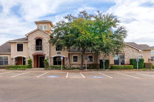Building exterior with parking lot and a large green tree