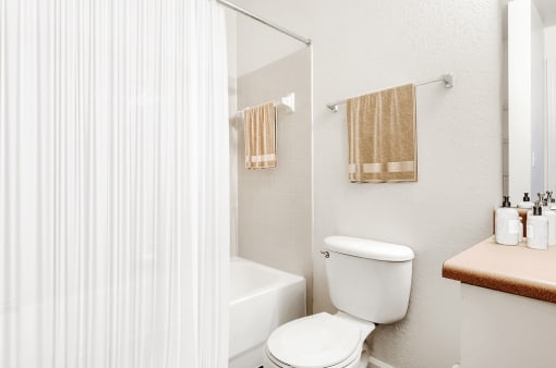 Virtually staged bathroom with a tiled tub, shower curtain, toilet