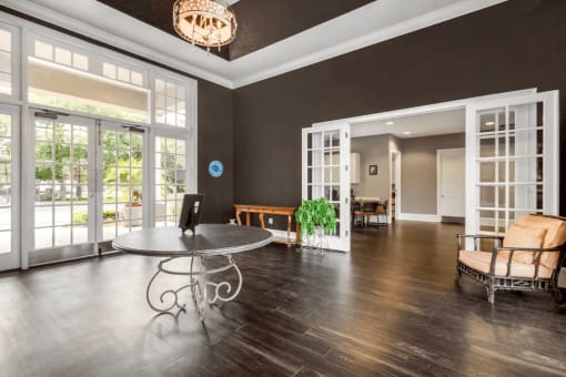 Clubhouse interior front door, chandelier, brown and tan chair, leasing office, wood style flooring, dark colored accent walls