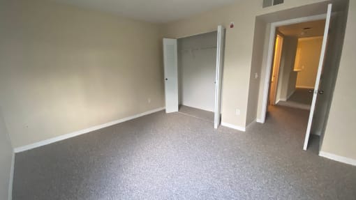 Carpeted bedroom with double door closet, double tone paint and bedroom door leading to hall