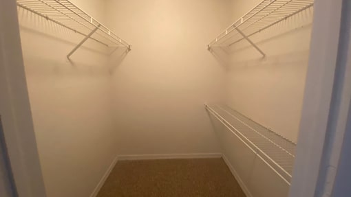 Spacious single door closet with mounted metal shelves