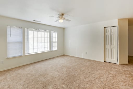 a bedroom with three windows and a ceiling fan