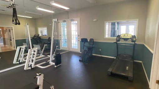 Fitness center with exercise bike, treadmill, elliptical, weight machines, and wall made up mirrors