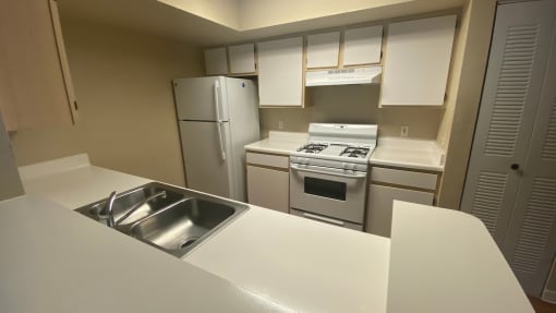 Kitchen featuring white cabinets, white appliances, white countertop, gas stove, folding door pantry