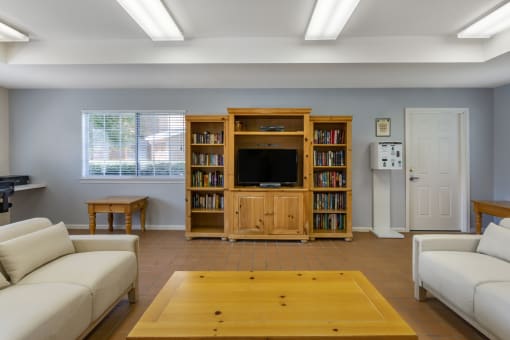 Clubhouse lounge with couches, coffee table, book shelving, and television