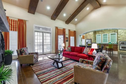 Clubhouse Interior with red and orange accents, a red sofa, orange curtains, two accent chairs, and a striped rug